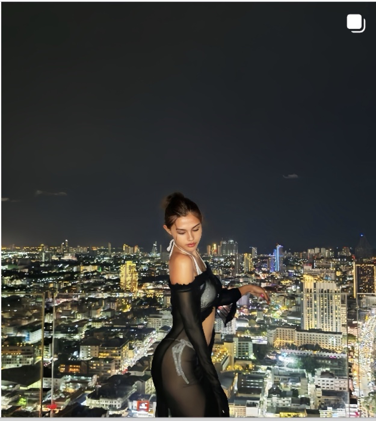 Tali in a black evening outfit with a city view